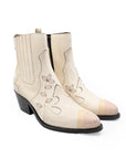 Pair of white cowboy boots with black accents on a white background