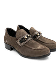 Pair of brown loafers with decorative straps on a white background