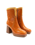 Pair of orange ankle boots with wooden soles on a white background