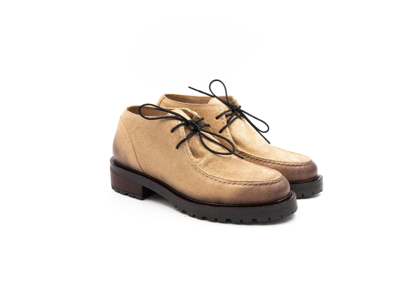 Pair of tan suede shoes with black laces on a white background