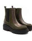 Pair of green Chelsea boots with black soles on a white background