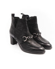 Black leather ankle boots with chain details on a white background