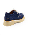 A blue suede shoe with a light-colored sole and lace-up closure, displayed against a white background.