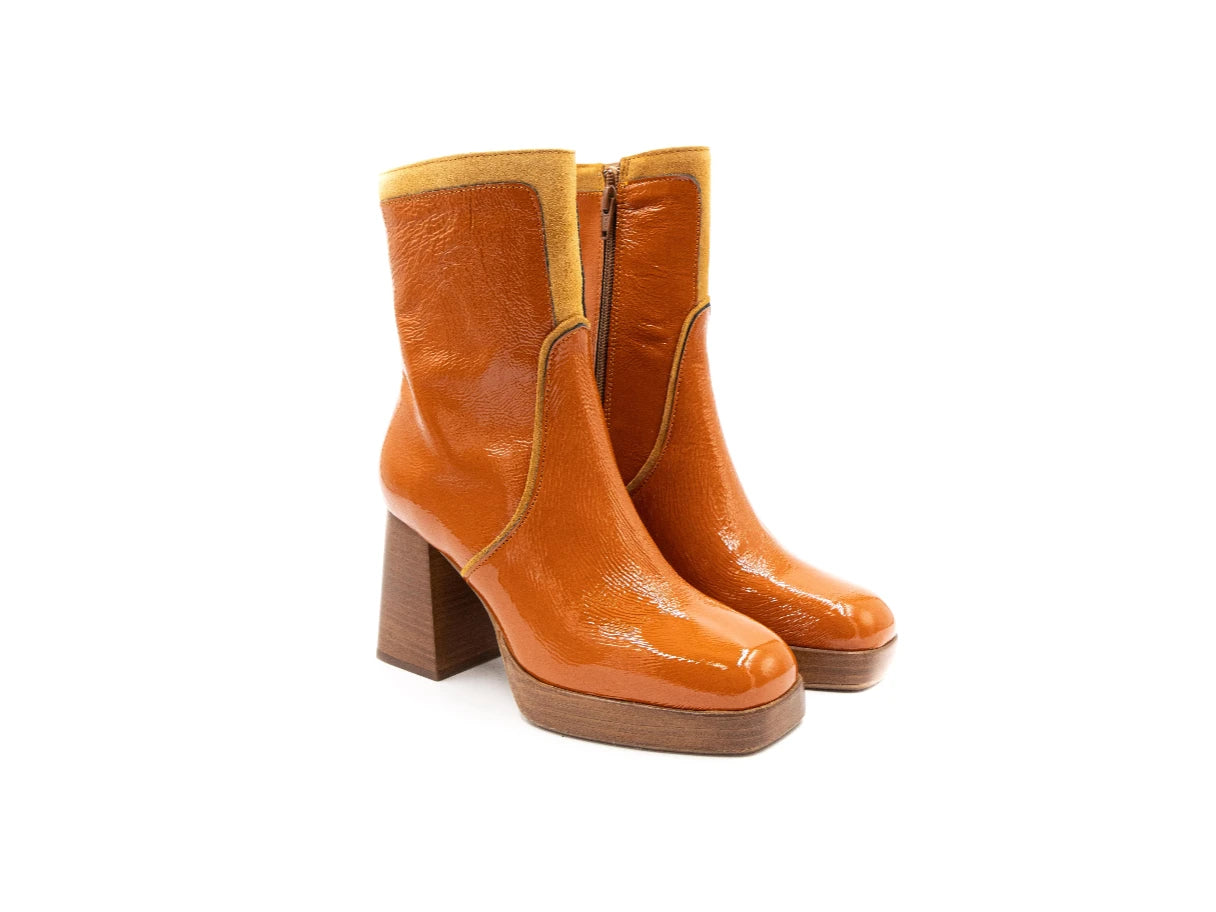 Pair of orange ankle boots with wooden soles on a white background