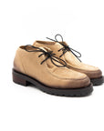 Pair of tan suede shoes with black laces on a white background